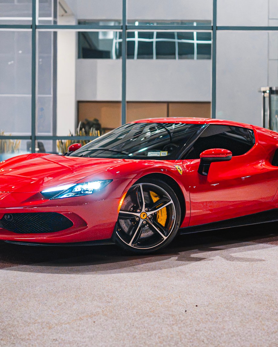 Our Fleet — a red supercar parked at night outside a glass lobby.